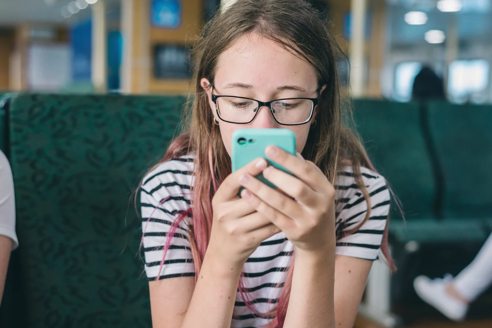 Teen staring at a glowing phone screen in a dark room, symbolizing social media addiction and isolation