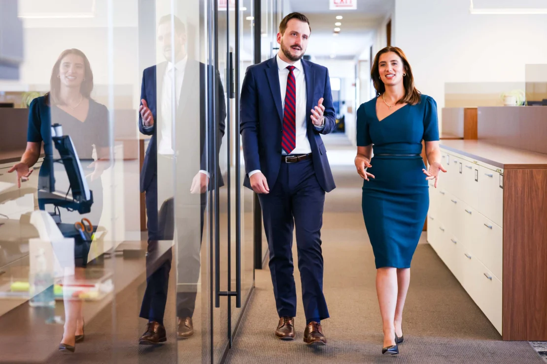 Two lawyers walking down a hallway in an office.