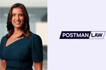A woman in a dark dress stands smiling in an office setting next to a logo that reads "Postman Law" on a light background.